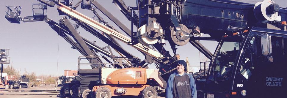student with large machine cranes behind him