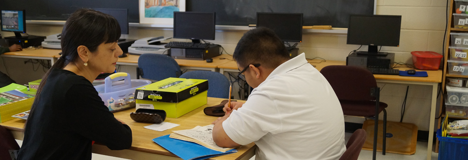 Male student working with teacher in a classroom