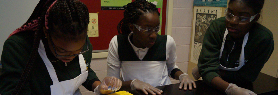Students wearing safety glasses and aprons in a science lab